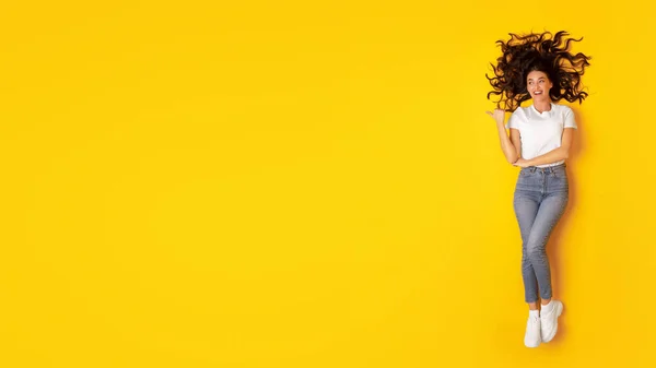 Şuraya Bak Copyspace Işaret Eden Neşeli Kadın Stüdyodaki Sarı Arkaplan — Stok fotoğraf