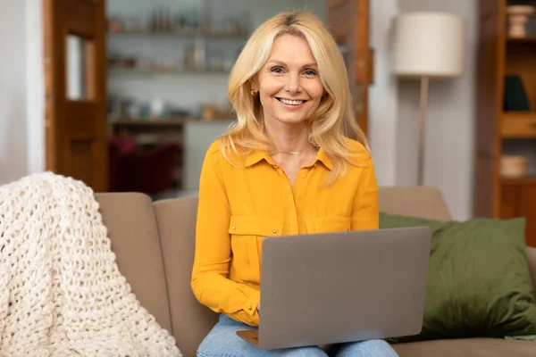 Neşeli Sarışın Olgun Bayan Dizüstü Bilgisayar Kullanıyor Evdeki Koltukta Oturan — Stok fotoğraf