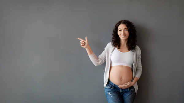 Smiling Expectant Mother Pointing Copy Space Her Tenderly Touching Belly — Stock Photo, Image