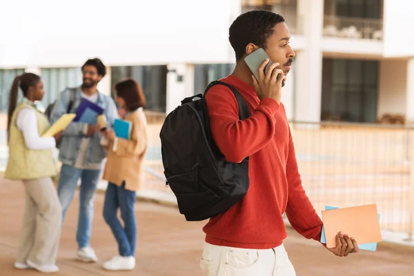 真剣に忙しいアフリカ系アメリカ人の男性学生は 電話でバックパックを呼び出し キャンパスの屋外で勉強とテストの準備ができています 大学での休憩 知識と現代的な学習 — ストック写真