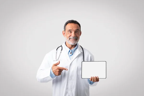 Cheerful European Senior Doctor White Coat Stethoscope Points Finger Tablet — Stock Photo, Image
