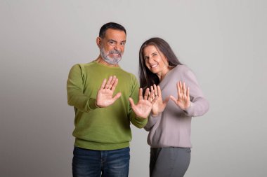 Üzgün, tatminsiz, beyaz, yaşlı bir adam ve bir bayan, gri stüdyo geçmişinden iğrenerek, dur hareketi yapıyorlar. Kötü teklif, hayal kırıklığı, yasak, reddedilme, kişisel alan