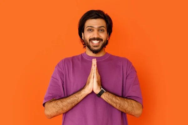 穿着紫色T恤 手牵着手 在镜头前微笑 在橙色工作室的背景下问候和感谢 快乐而又英俊 留着胡子的印度年轻人 — 图库照片