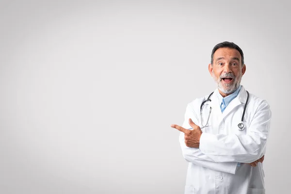 Χαμογελώντας Σοκαρισμένος Ευρωπαίος Ανώτερος Γιατρός Ανοιχτό Στόμα Λευκό Παλτό Δείχνει — Φωτογραφία Αρχείου