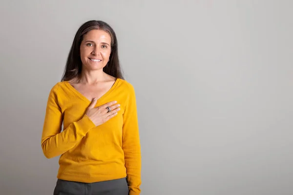 快乐漂亮的高加索老太太把她的手放在胸前 在灰色的工作室背景上做感恩手势 复制空间 好消息 谢谢你的签名 广告和提供 人们的情感 — 图库照片