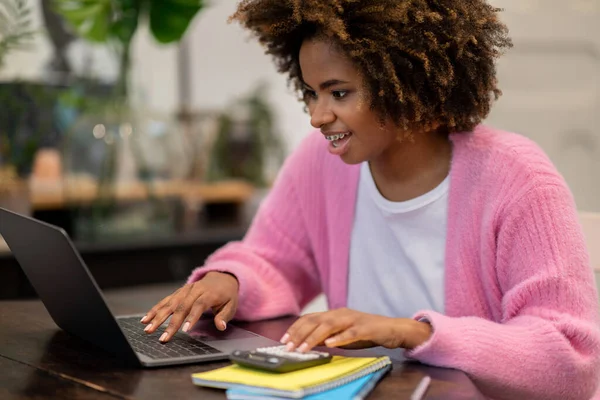家庭で働くフリーランスの家庭で働く幸せな笑顔の千年の黒人女性は ノートパソコン 電卓を使用して コンピュータのキーボード コピースペースを入力し リビングルームでソファに横になります リモートジョブコンセプト — ストック写真