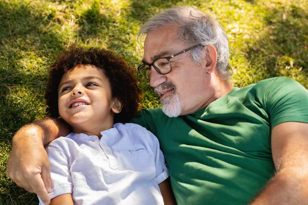 Olumlu Yaşlı Beyaz Büyükbaba Küçük Melez Çocuğa Sarılıyor Yeşil Çimlerin — Stok fotoğraf