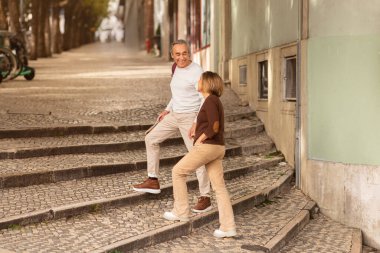 Mutluluğa giden merdiven. Neşeli olgun gezginler Lizbon 'un büyüleyici sokaklarında el ele yürüyen çiftler. Kıdemli Turistlerin Avrupa 'da Yürüyüşünün Tam Uzun Çekimi