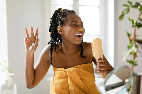 Juguetona Dama Negra Cantando Mientras Cepilla Cabello Sosteniendo Cepillo Madera —  Fotos de Stock