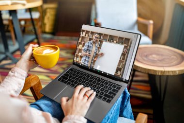 Kafedeki masada oturan, kahve içen ve dizüstü bilgisayar kullanan, tanınmayan bir bayan, yakışıklı bir adamla video görüşmesi yapan, omuzlarının üstünden fotoğraf çeken, online eğitim için kolaj yapan bir kadın.