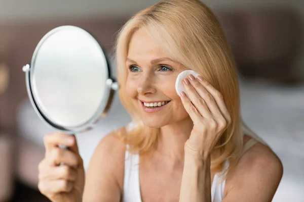 Güzel Yaşlı Bir Kadın Pamuklu Bezle Cildi Temizliyor Aynaya Bakıyor — Stok fotoğraf