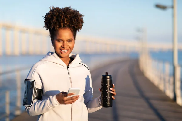 Mujer Deportiva Negra Con Botella Fitness Smartphone Relajante Después Entrenamiento — Foto de Stock