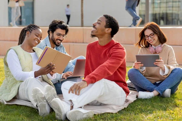 陽気な留学生千年生の勉強 リラックス 芝生の上で座って 大学の屋外でタブレットでオンラインレッスンを見てください チャット ブログ ソーシャルネットワーク 休憩や教育 — ストック写真
