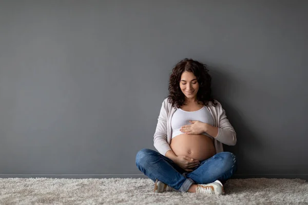 Bebek Beklentisi Gri Duvarın Yanında Otururken Hamile Karnını Kucaklayan Güzel — Stok fotoğraf