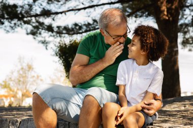 Yaşlı beyaz adamın küçük melez çocuğa sarılıp kulağına sır fısıldayarak dışarıda vakit geçirmesine sevindim. Dedikodu, iyi haber, gizem, parkta birlikte yürümek, aile ilişkisi, reklam ve teklif