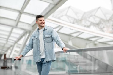 Havaalanı Beklentisi. Gezici bavullu neşeli gezgin modern terminalde kalkışa hazır bekliyor, kopyalama uzayına bakıyor. Keyifli Yolculuklar ve Ulaşım Teklif