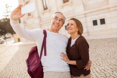 Tatilde. Mutlu Olgun Turistlerin Eşleri Açık havada sırt çantasıyla selfie çekerek akıllı telefon pozu veriyor. Kıdemli Seyahat Blogcuları Lizbon Maceralarını Belgeliyor Şehirde Eğleniyorlar