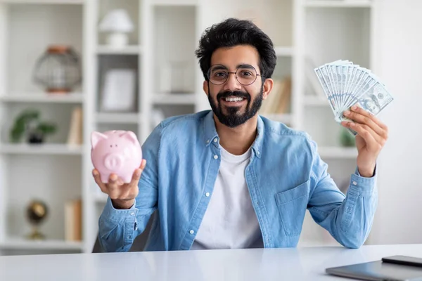 Smiling Young Indian Man Holding Piggy Bank Dollar Cash While — Fotografia de Stock