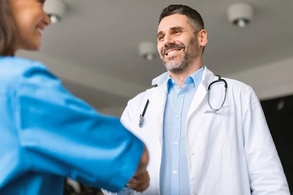 快乐的男性医务长在诊所聘请欢迎新的队友 开业医生与女同事握手 感谢她的帮助和帮助 — 图库照片