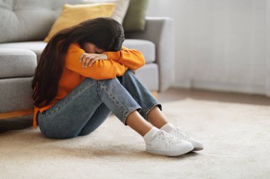 Depresyon kavramı. Evinde ağlayan üzgün genç bir ortadoğulu kadının portresi, depresyonda olan bin yıllık bir kadın, başını dizlerine gömen, odada oturan, zihinsel çöküntü çeken, kopyalayan uzay