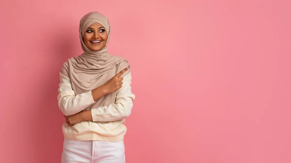 广告的位置 头戴头巾 头戴粉红头巾 快乐美丽的阿拉伯女士 带着手指在复印空间旁边指指指点点的穆斯林女性 — 图库照片