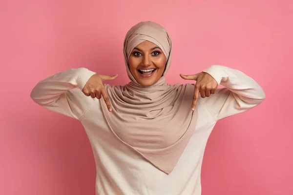 看那里 头戴头巾 面带微笑的伊斯兰女人 站在粉色背景之上 展示你设计或广告的复制空间 — 图库照片