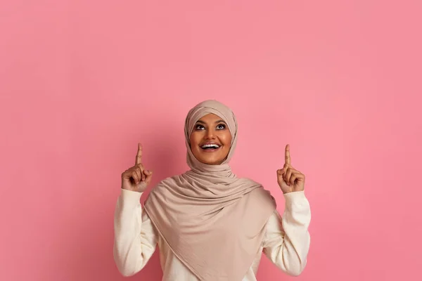 看那里 喜气洋洋的阿拉伯妇女 身穿头巾 头戴头巾 头戴粉色背景 两只手高举复印空间 高高兴兴的穆斯林妇女 头戴头巾 站在粉色背景下 — 图库照片