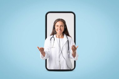 Dijital kronik hastalık yönetimi. Kulaklıklı neşeli yaşlı kadın doktor konuşuyor ve işaret ediyor, mavi stüdyodaki büyük akıllı telefondan bakıyor. İlaç servisi uygulaması