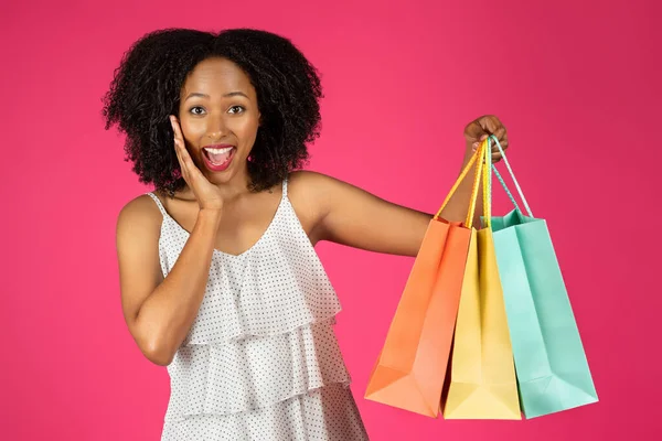 購入の多くのパッケージを持つ陽気な驚きのミレニアムアフリカ系アメリカ人の巻き女性は ピンクの背景 スタジオに隔離されたオンラインショッピングをお楽しみください ショパホリック セール ファッション ギフト — ストック写真