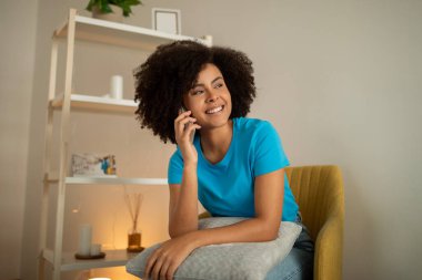 Zeki telefondan arayan, oturma odasının içindeki arkadaşıyla konuşan neşeli, güzel, siyah kıvırcık kadın. Boş alana bak. İyi haber, iletişim, evde dedikodu.