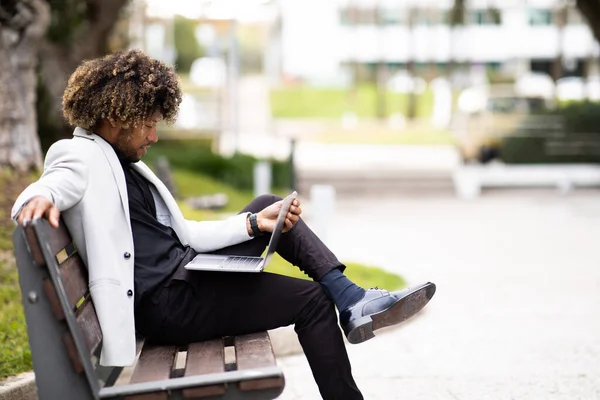 Μαύρος Επιχειρηματίας Κοστούμι Χρησιμοποιώντας Φορητό Υπολογιστή Ενώ Κάθεται Στον Πάγκο — Φωτογραφία Αρχείου