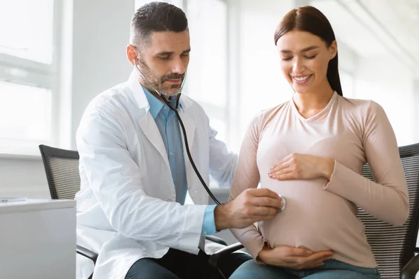 孕妇和婴儿的健康 男医生在医院为年轻女士预约时倾听婴儿的心脏 在诊所看妇科医生的年轻女病人 — 图库照片