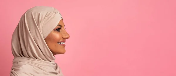 在演播室里看粉色背景上的复制空间 头戴头巾的快乐美丽的伊斯兰女人的侧面照片 你的广告横幅 — 图库照片