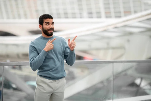 旅游门票提供 位于现代机场候机楼室内的免费航天广告运输处外的兴奋的阿拉伯男子指点着手指 看那里的概念 — 图库照片