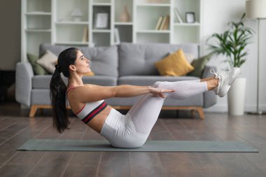 Zayıf, sportif, çekici, esmer kadın dar beyaz spor giyimli spor giyimli, spor minder üzerinde egzersiz yapan kadın, evde yoga ya da pilates egzersizi yapan kadın, sabah fiziksel aktivite konsepti.