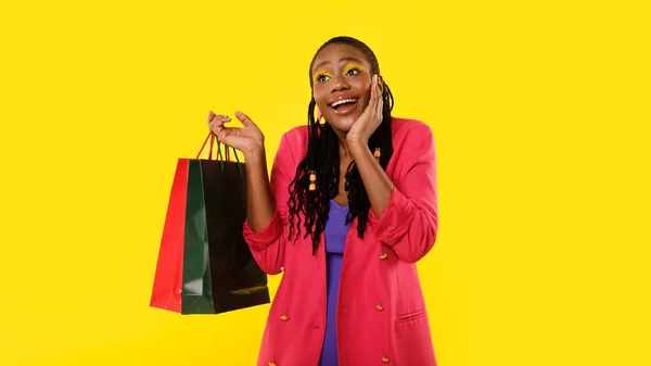 夢のショッピング 正黒女性バイヤーポージングでペーパーショッパーバッグ タッチ顔で興奮広告販売オファー以上イエロー背景 スタジオショットパノラマ — ストック写真