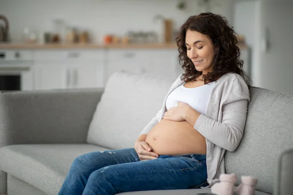 Mujer Embarazada Acariciando Suavemente Bulto Del Bebé Mientras Relaja Sofá — Foto de Stock