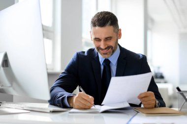 Başarılı bir girişimcilik kariyeri var. Mutlu orta yaşlı işadamı gazete ve iş raporları okuyor, işyerinde oturuyor, muhasebe ve belgelerle uğraşıyor.