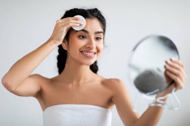 Neşeli Hintli Kadın Aynayı Tutuyor ve Cilt Temizlemek İçin Pamuk Pedi Kullanıyor, Banyo Havlusuna Sarılı Doğulu Gülümseyen Genç Kadın Evde Günlük Güzellik Yapıyor, Kapanış Portresi