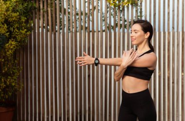 Spor giyimli neşeli, genç, beyaz bir bayan el esnetme ve ısınma hareketleri yapıyor, dışarıda spor yapmanın tadını çıkarıyor. Spor, spor, kilo kaybı, sağlık hizmetleri ve şehirde motivasyon