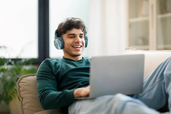 Oferta Learningu Wesoły Arabski Facet Wpisując Websurfing Laptopie Bezprzewodowymi Słuchawkami — Zdjęcie stockowe