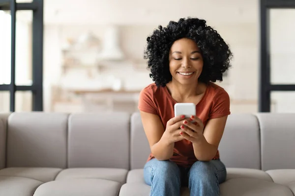 Akıllı Telefonlu Gülümseyen Siyah Bir Kadın Evde Koltukta Dinleniyor Koltukta — Stok fotoğraf