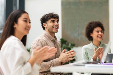 İş Başarı Kutlaması. Bir grup neşeli iş arkadaşı el çırpıyor ve modern ofiste yan yana oturuyorlar. Birlikte Başarı Kutlaması 'na katılan üç meslektaşım. Seçici Odaklanma