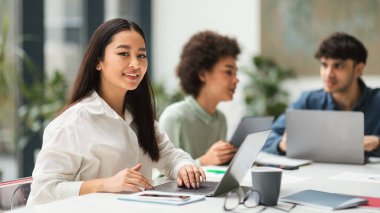 Kendine güvenen Asyalı iş kadını Laptop kullanıyor çeşitli iş arkadaşlarıyla Modern Ofis 'teki masada oturuyor. Başarılı bir iş kariyeri. Panorama, Seçici Odaklanma