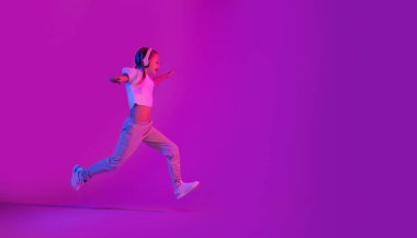 Yüksek Teknolojik Öğrenme Geleceği. Genç kız interaktif öğrenmenin yeni bir türünü yaşıyor, renkli arka planda çalışıyor, kablosuz kulaklık kullanıyor, bağlanma ve eğlenceli eğitimden hoşlanıyor, yer kopyalıyor.