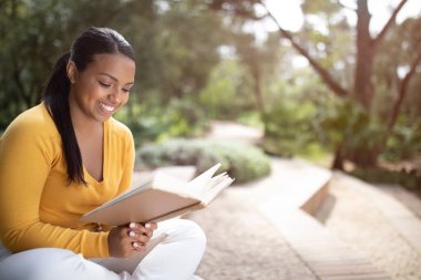 Gülümseyen Brezilyalı bayan öğrenci kampüste dinleniyor ve kitap okuyor ya da dışarıda park ediyor, fotokopi çekiyor. Üniversite ilanında öğrenim, bilgi, eğitim ve yaşam tarzına ara verip