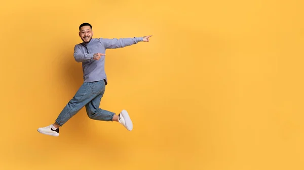 Spójrz Cherful Azjatycki Mężczyzna Wskazując Bok Podczas Skakania Powietrzu Pozytywny — Zdjęcie stockowe