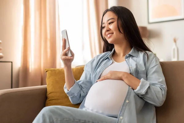 Беременность Гаджеты Счастливая Беременная Корейка Пользуется Социальными Сетями Сидит Дома — стоковое фото