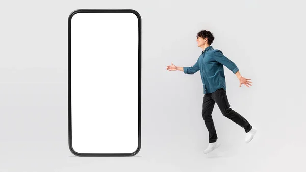 Fröhlicher Mann Springt Auf Großes Handy Mit Leerem Bildschirm Träumt — Stockfoto