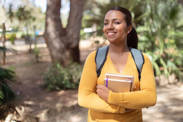 一个成功的学生女孩的画像 一个拿着书本 微笑着看着站在大学校园里或停在外面的相机的女士 学习概念 — 图库照片